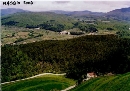 panoramica dal costone della ex cava di serpentino delle Volpaie ai Sassi Neri verso la valle del torrente Bagnolo, si vedono in basso a dx il centrovisite, il corpo della discarica a dx e sx ricoperto da un verde manto erboso, sgombro da alberi; sulla sx al limitare del bosco la strada poderale che sale dalla frazione di Bagnolo, sullo sfondo le montagne dellappennino prato-pistoiese
