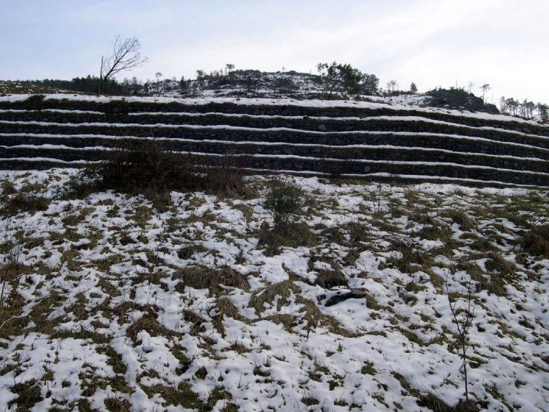 i gradoni che sorreggono il terreno a ricoprimento della discarica, in abito invernale.